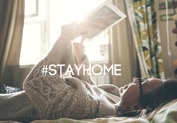 woman lying in bed with digital tablet touching with finger in morning sunlight