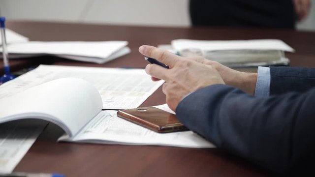 Male hand holding pen in corporate meeting room. Man talking anf discussing a new project at group meeting about company achievement