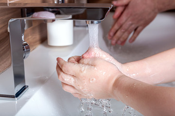 Father and child wash their hands together with soap and water during quarantine of coronavirus. Teaching children clean and healthy manners against bacteria viruses. Parenthood concept.