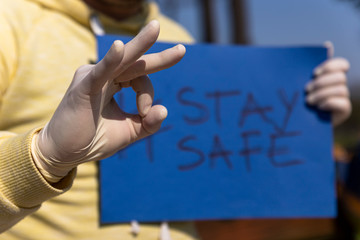 Stay safe sign on blue chroma key paper held by a man in surgical gloves giving ok sign with hand