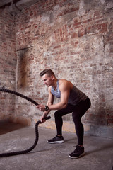 man is engaged in the gym with ropes