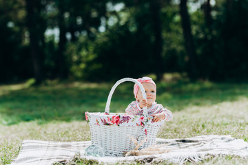 The child sits in a white basket. Child with basket on nature.