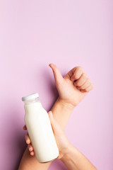 Glass bottle with coconut detox drink in woman hand over purple