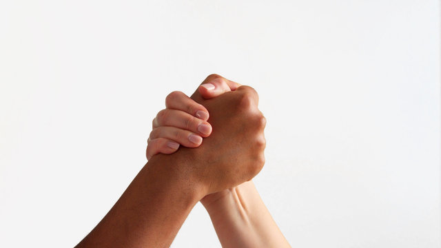 arm wrestling between male hand and female hand with different skin tones on white