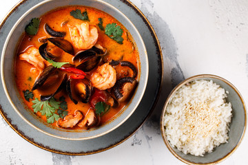 rich Tom Yam with seafood, shrimp and mushrooms close-up on a white background