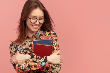 A young pretty girl student, with books from the library, smiling sweetly. Distance learning of foreign languages.