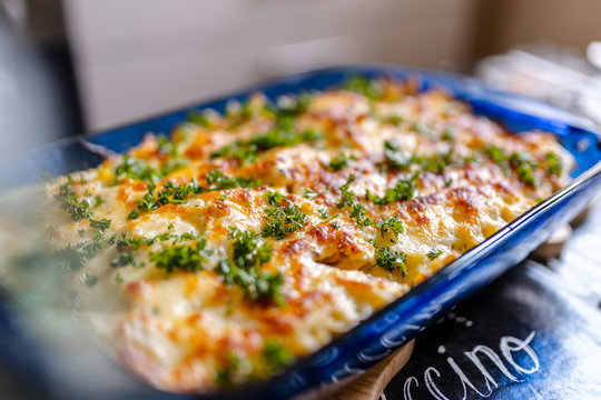 Cheese and noodles casserole in blue bowl, garnished with parsley