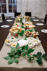 Table full of different interesting and tasty dishes on banquet in restaurant. Variety of plates with salads, assorted meat and cheese, bruschettas and canapes. Food concept.