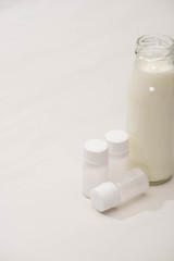 High angle view of bottle of homemade yogurt near containers with starter cultures on white background