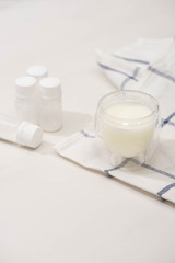 Selective focus of glass of homemade yogurt on cloth near containers with starter cultures on white