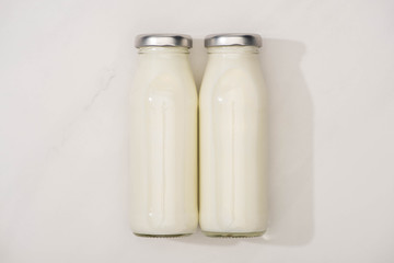 Top view of bottles of homemade yogurt on white background