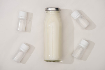 Top view of bottle of homemade yogurt and containers with starter cultures on white background