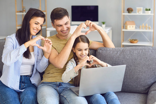 Online Video Chat Online. Family Holds Hands In The Shape Of A Heart Welcomes Waving Friends Using Laptop At Home.