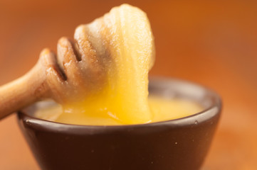 honey pour from a wooden spoon into a clay plate
