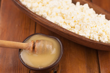 Cottage cheese in clay bowl and honey on wood table background. Dairy products and honey with copy space