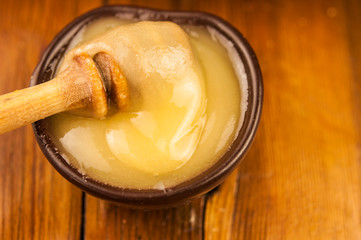 honey pour from a wooden spoon into a clay plate