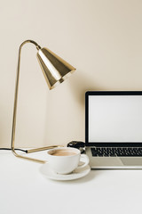 Blank screen laptop. Home office desk table workspace with coffee, lamp on beige background. Copy space mockup blog, website template. Blogger, outsourcing freelancer hero header.