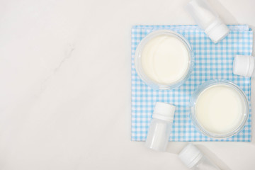 Fototapeta na wymiar Top view of glasses of homemade yogurt and containers with starter cultures on cloth on white background