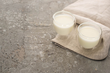 High angle view of glasses of homemade yogurt on beige cloth on grey background