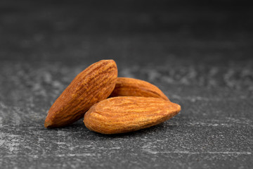 Side view closeup on the almond nuts on the grey scratched background, horizontal format