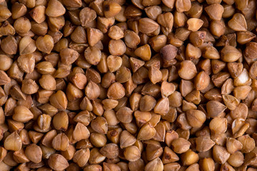 Top view close up macro on brown healthy uncooked buckwheat groats, horizontal format