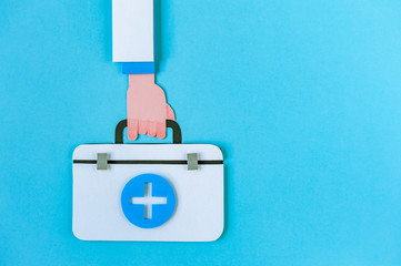 Doctor hand hold first aid kit on blue background. World Health Day. Healthcare concept. Space for text. Soft focus. Top view.