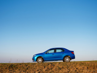 Fototapeta premium Belarus blue car in a field in spring at sunrise