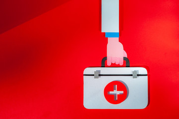 Doctor hand hold first aid kit on red background. World Health Day. Healthcare concept. Space for...