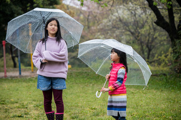 雨の日に公園で遊んでいる子供姉妹