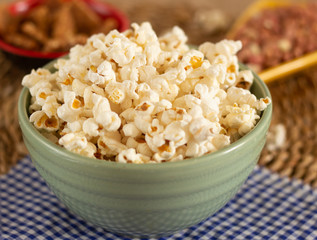 big bowl full of popcorn  surrounding by peanuts candies on the straw background