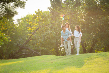 Fototapeta premium Happy family playing on the grass in the park at sunset. The concept of a happy family.