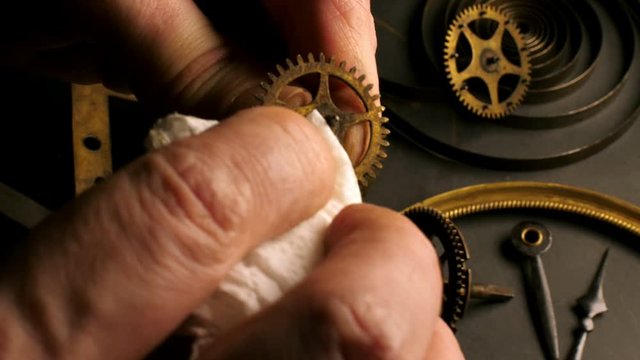 Closeup of a retro clock mechanism cleaning. Old dirty gear wheel.