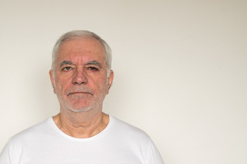 old man senior  white shirt closeup next to the wall healthy unhappy overexposed not in focus