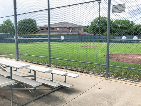 Vacant bleachers near empty baseball field with metal chain link in Dallas, Texas, USA
