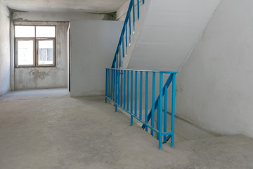 indoor Concrete Staircase With blue iron steel Handrail, light from window on background.