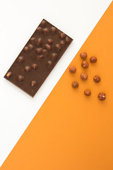 Dark chocolate with hazelnuts on the two-color background. Location vertical. Top view. Copy space.