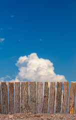 Fence from tree bark to sky clouds.