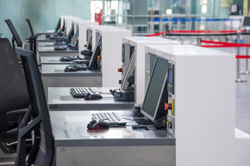 Row of empty check-in desks with computer monitors at the airport.
