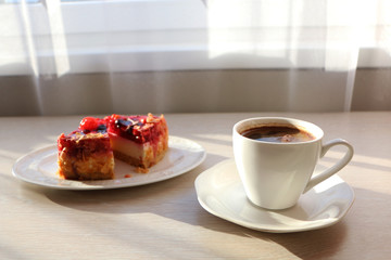 Concept - close up of a mug with coffee and cake on the table.