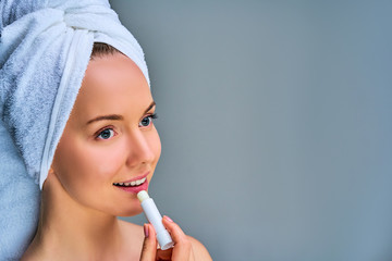Closeup naked girl with white bath towel on hair moisturize paints lips. Beauty concept