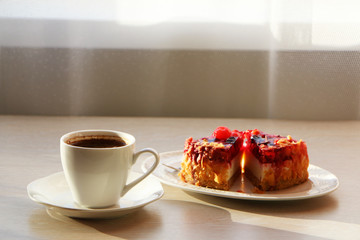 Concept - close up of a mug with coffee and cake on the table.