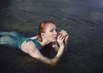 beautiful red-haired girl bathes in a stormy stream, hot summer