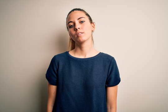 Young beautiful blonde woman with blue eyes wearing casual t-shirt over white background Relaxed with serious expression on face. Simple and natural looking at the camera.