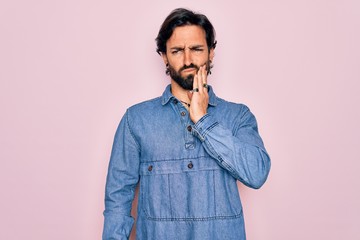 Young handsome hispanic bohemian man wearing hippie style over pink background touching mouth with hand with painful expression because of toothache or dental illness on teeth. Dentist