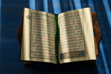 Quran and rosary beads on the white background with blue candle for Islamic concept. Holy book...