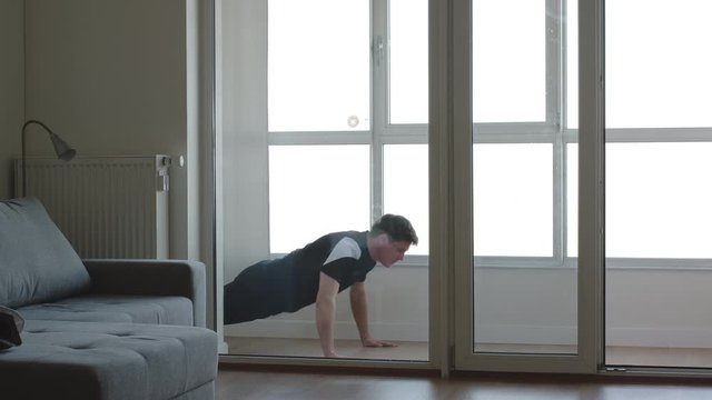 Young man exercising. Doing push-ups in the balcony. Home wellness training.