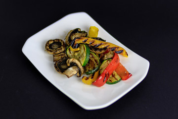 Grilled vegetables salad with zucchini, sweet pepper, mushrooms. Vegeretian restaurant meal on a white plate.