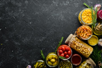 Food stocks in glass jars. Pickled vegetables. On a black background. Top view.