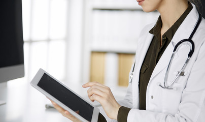 Unknown female doctor using tablet computer in clinic. Perfect medical service in hospital. Medicine concept