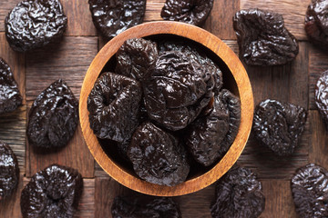 dried plums, prunes in wooden bowl, top view.